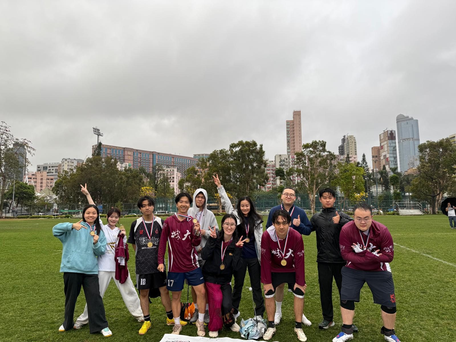 Club members posing together with medals on a grass field